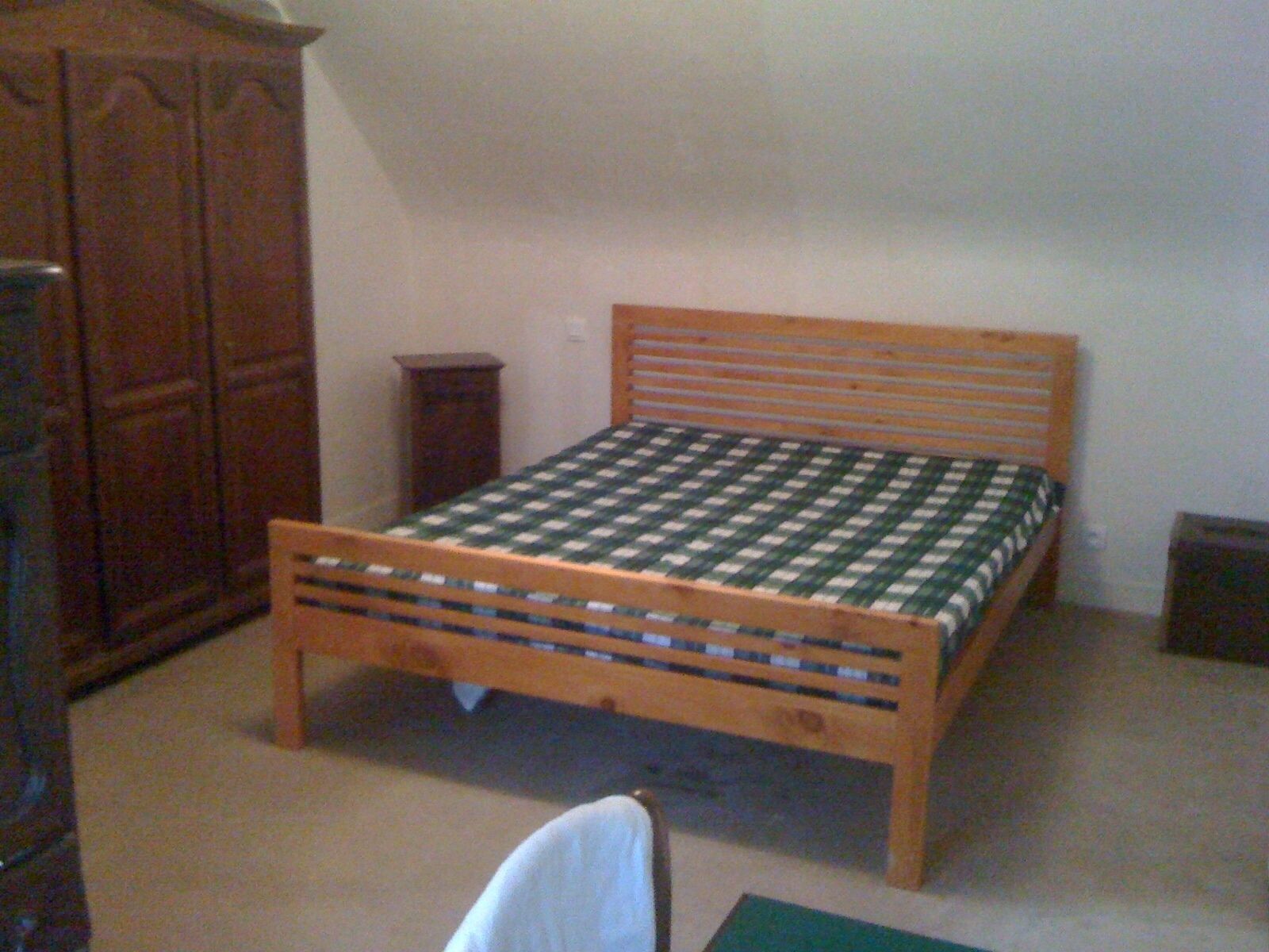 A small, single-bed room with a wooden bed frame and a checkered bedspread.
