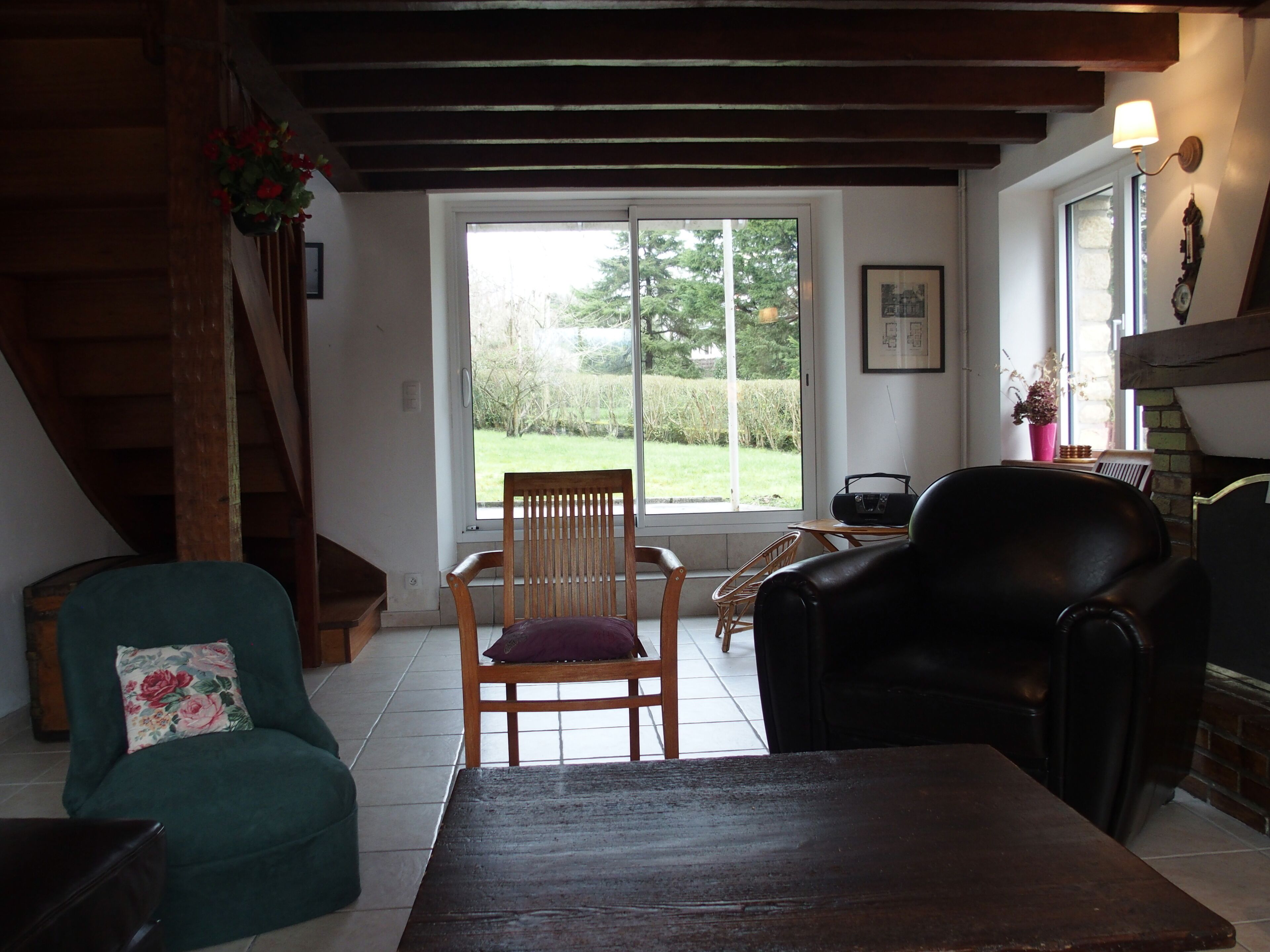 Uma sala de estar acolhedora com uma cadeira de madeira, um poltrona verde, um sofá preto e uma mesa de madeira.