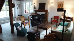 Een gezellige woonkamer met een open haard, houten meubels en uitzicht door grote ramen.