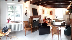 Een gezellige woonkamer met een open haard, houten meubels en uitzicht op het omliggende landschap.