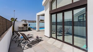 A modern outdoor patio with a pool, lounge chairs, and a barbecue area. - Modern & bright, only a short walk into the town centre, A/C & heated pool (Playa Blanca)