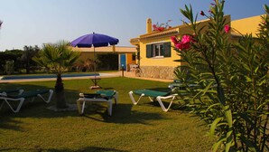 Area piscina con lettini e un ombrellone blu.