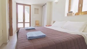 Un dormitorio con cama, silla y ventana.