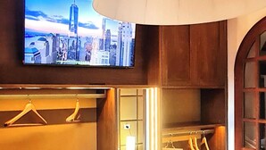 A hotel room with a bed, a TV mounted on the wall, a wardrobe, and a hanging light fixture. - Franco House in the Old Town (Marina di Campo)
