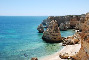 A coastal landscape with clear blue waters, rocky formations, and a sandy beach. - Apartment with air conditioning, quiet residence with pool, close to beaches (PORCHES)