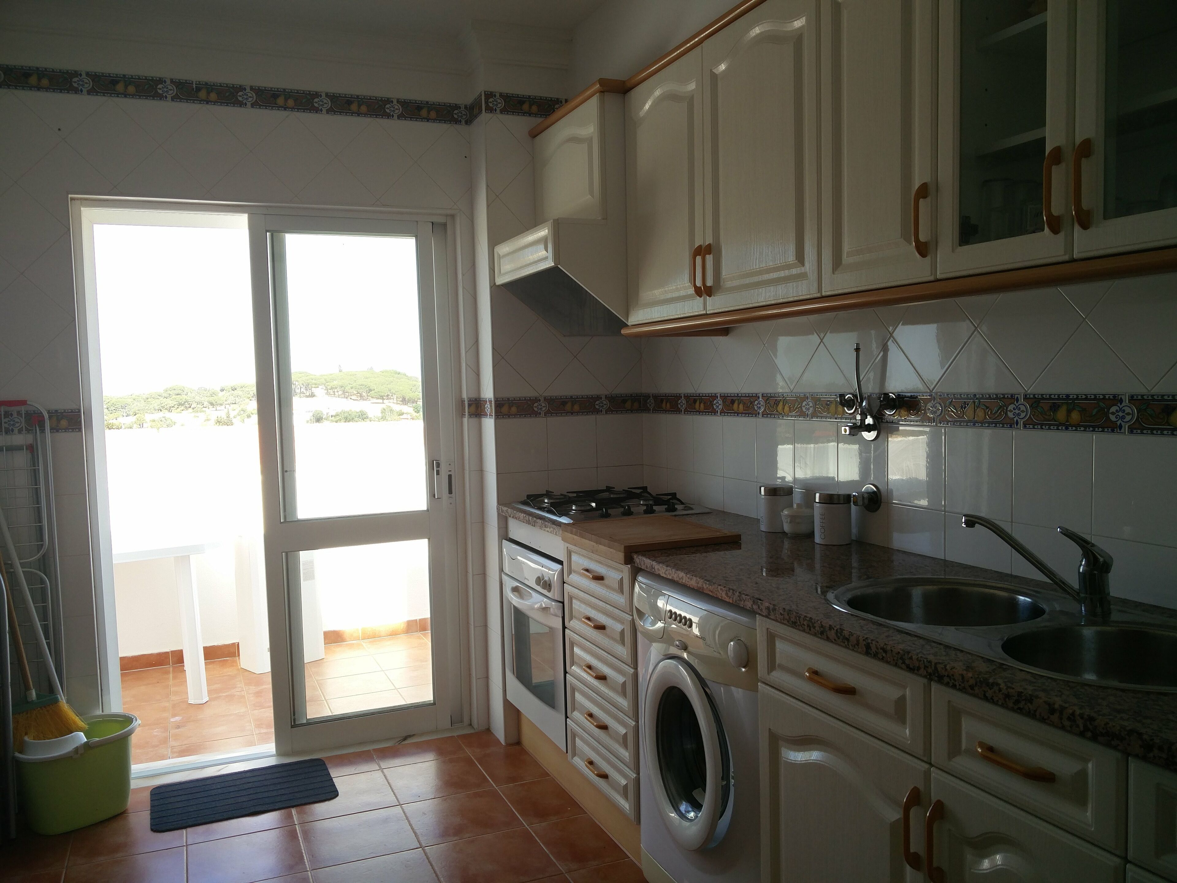 A kitchen with a washing machine, stove, sink, and cabinets.