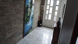 A hallway with a brick wall, a large poster of a waterfall, and a door with multiple windows.