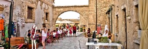 A narrow street with stone buildings, outdoor seating, and a variety of shops and stalls. - beautiful apartment in villa, private beach with umbrellas and sunbeds (Marzamemi)
