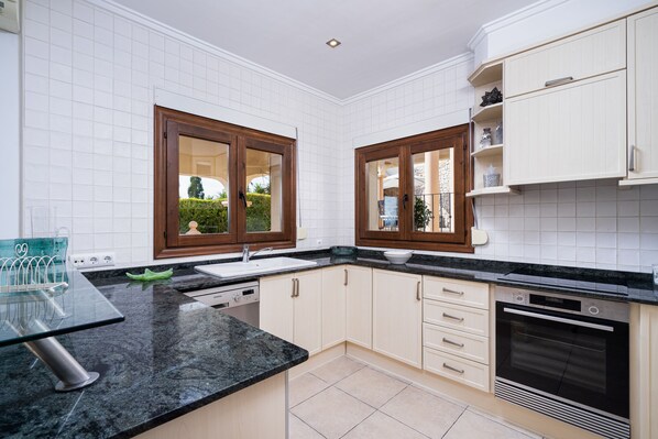 A modern kitchen with white cabinets, a black countertop, and a built-in oven.
