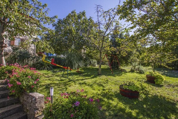 A garden with a playground, stone steps, and potted plants. - Seaside Bliss: Unwind in Your Exclusive Summer Rental Paradise (Labin)