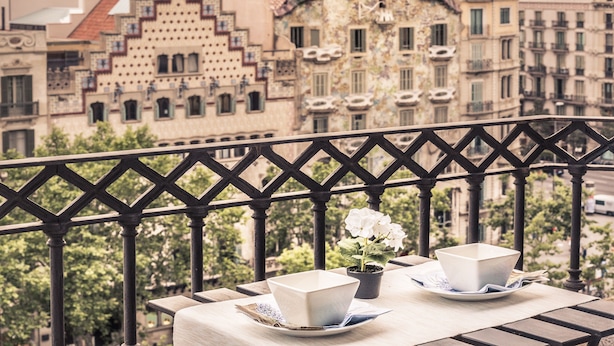 A balcony with a table set for two, overlooking a cityscape with historic buildings.