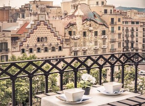 A balcony with a table set for two, overlooking a cityscape with historic buildings. - UNIQUE Paseo de Gracia CASA BATLLÓ Barcelona Center (Barcelona)
