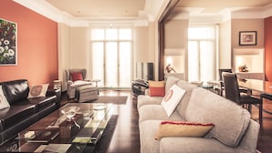 A spacious living room with a sofa, armchairs, a coffee table, and a dining area with a table and chairs.