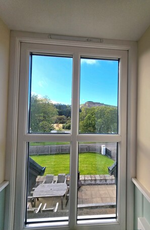 Ein Zimmer mit einem großen Fenster und Blick auf eine Wiese und einen Hügel.
