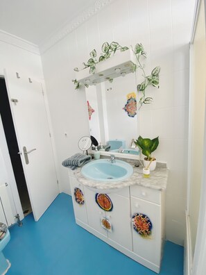 A bathroom with a blue sink, white cabinets, and decorative tiles. - WELCOME TO PARADISE (Coin)