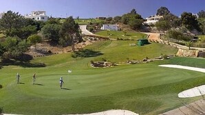Ein Golfplatz mit freiem Blick auf das Grün, Sandbunkern und umliegenden Bäumen.