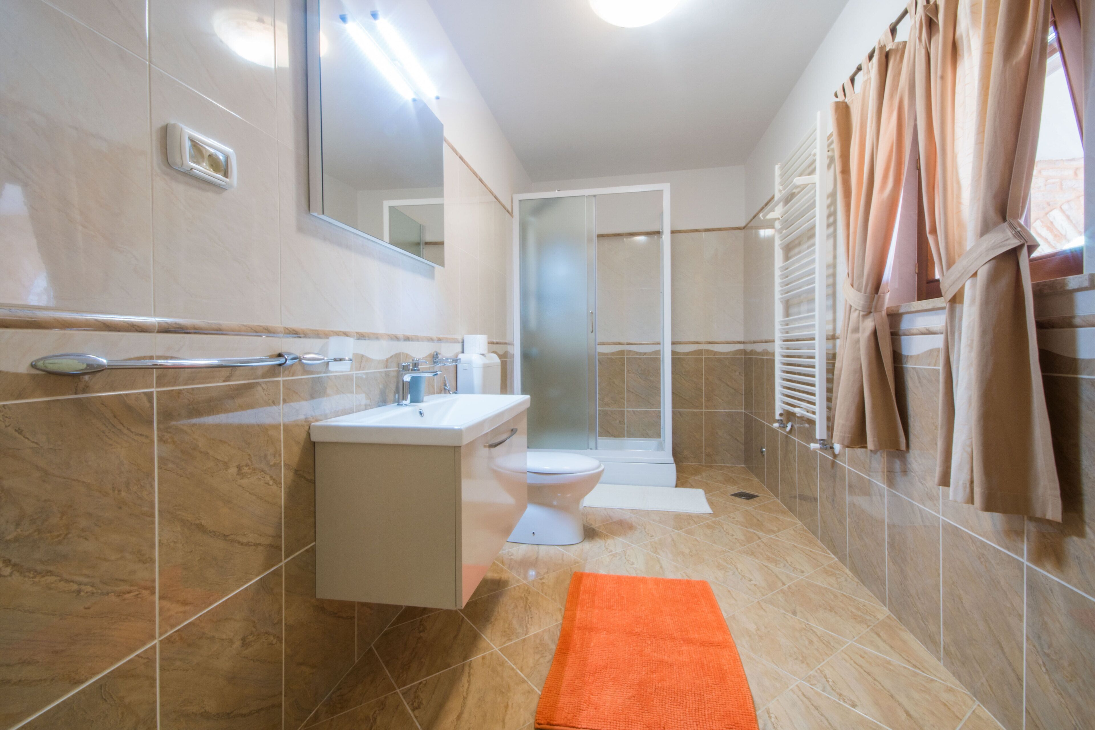 Een moderne badkamer met een douche, toilet en wastafel.