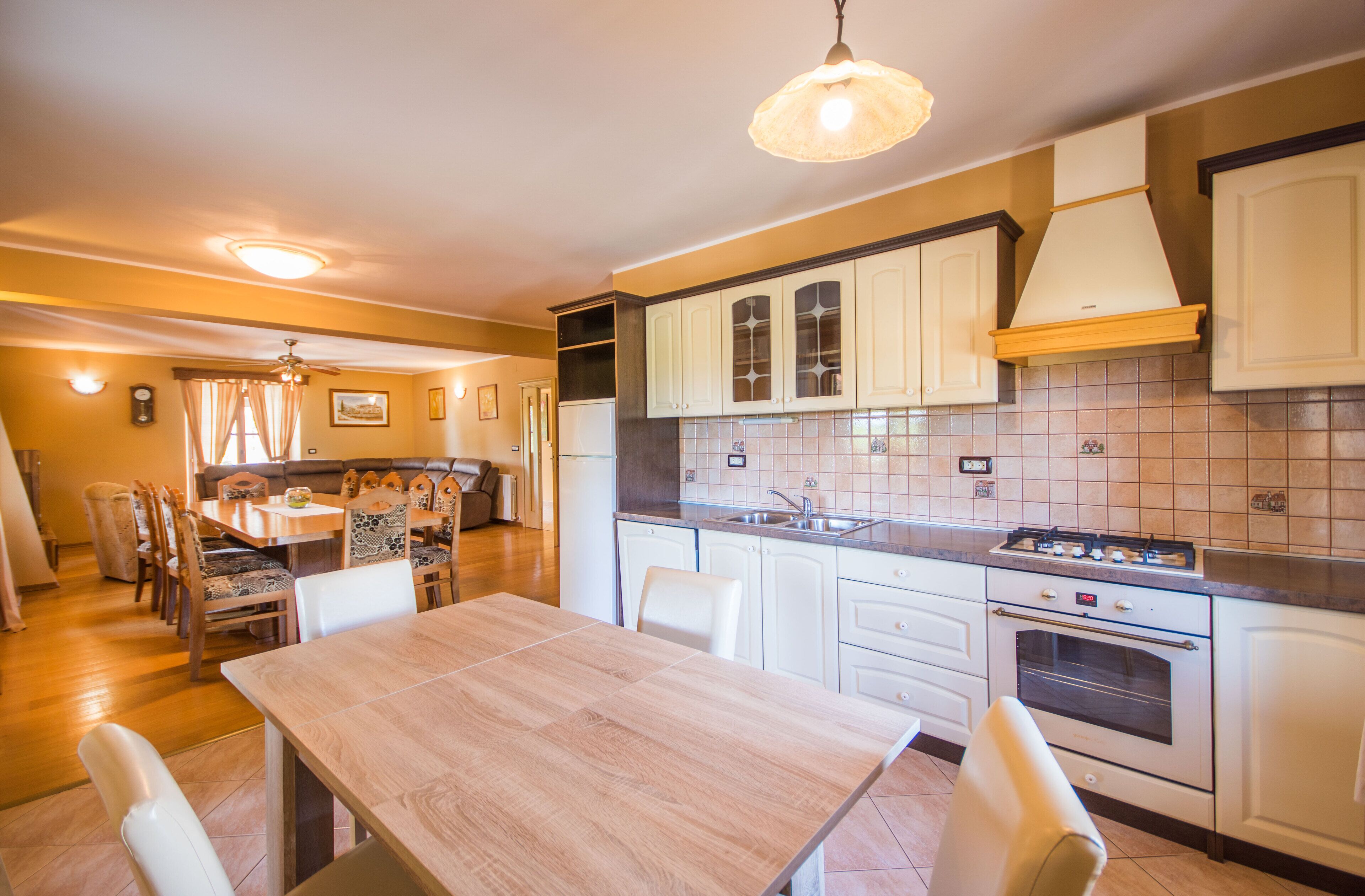 A kitchen with white cabinets, a wooden dining table, and a tiled backsplash.