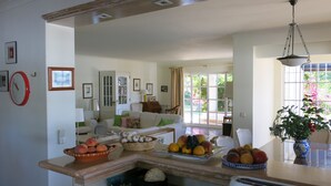 Uma sala de estar espaçosa com uma grande janela, uma área de jantar com potes de frutas e um canto de estar aconchegante.
