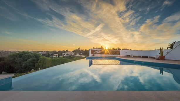 Piscina com vista para o pôr do sol e paisagem ao redor.
