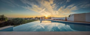 Une piscine offrant une vue sur le coucher du soleil et le paysage environnant.