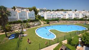 Una piscina de diseño curvo, rodeada por un área cercada con césped y árboles.