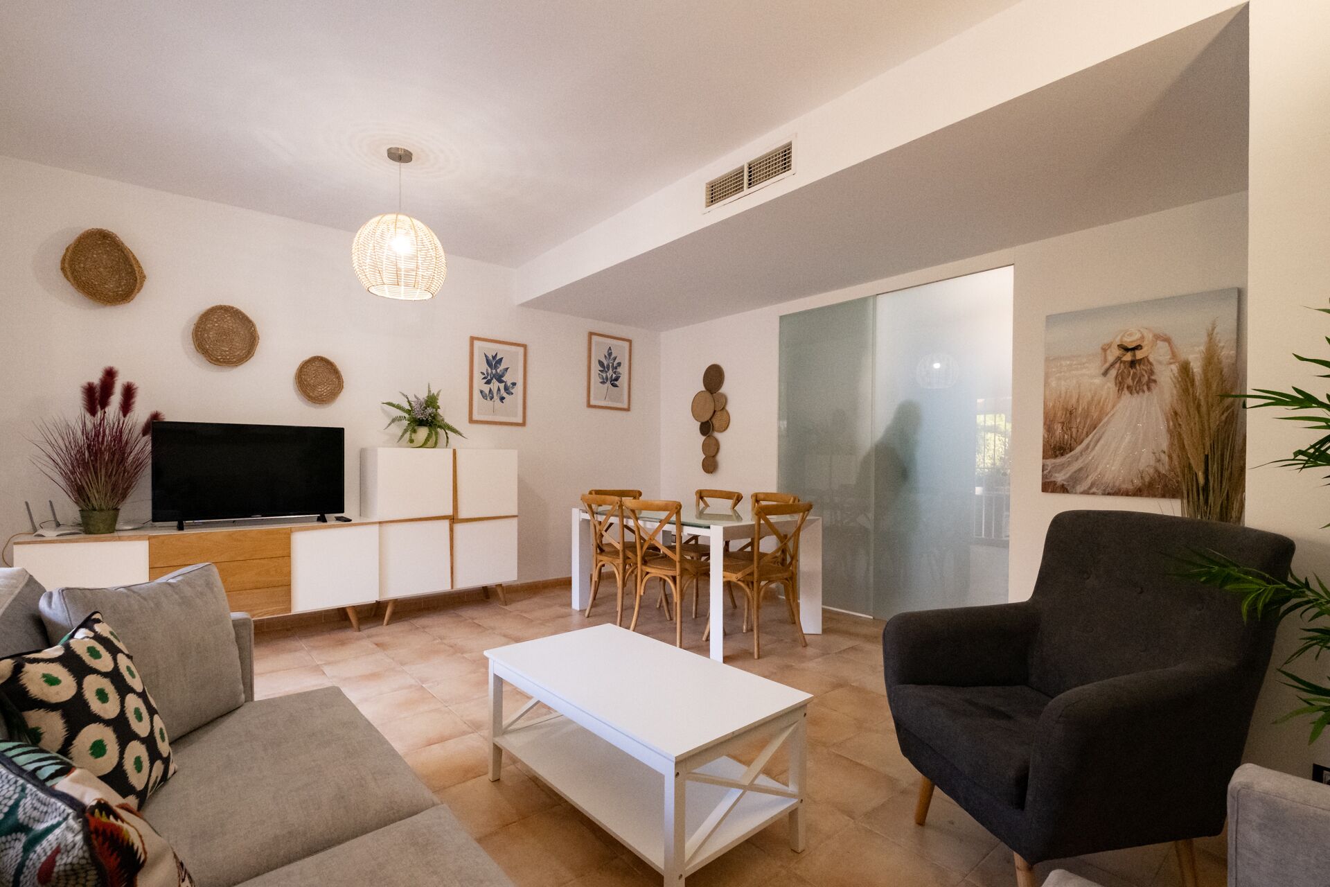 Un salon moderne avec un canapé, une table basse et un téléviseur posé sur un meuble. On y trouve également un coin repas avec des chaises et une table.