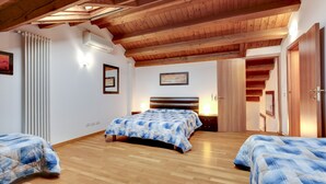 Ein Schlafzimmer mit zwei Betten, Holzboden, schrägem Dach und einem gerahmten Bild an der Wand.