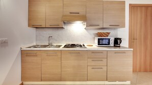 Eine moderne Küche mit Holzausstattung, einem Gasherd, einer Mikrowelle und einer Kaffeemaschine.