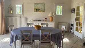 A dining area with a round table, white chairs, a bowl, a lamp, and a painting on the wall. - House / Villa - Le Rayol-Canadel (Rayol-Canadel-Sur-Mer)
