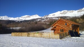 A wooden cabin with a sloped roof, surrounded by a wooden fence, set against a backdrop of snow-covered mountains and a clear blue sky. - Country Cottage / Gite - CHORGES (CHORGES)