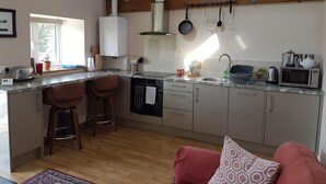 A modern kitchen with a built-in island, bar stools, a dishwasher, and a microwave.