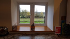 A kitchen with a window seat overlooking a grassy area.