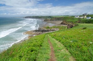 A coastal path leading to a beach with houses in the background. - Spacious, Quality, Pet Friendly Barn Conversion. In lovely rural setting. (Haverfordwest)