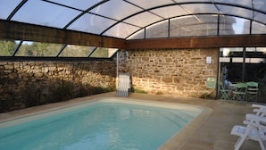 A swimming pool with a stone wall and a glass roof.