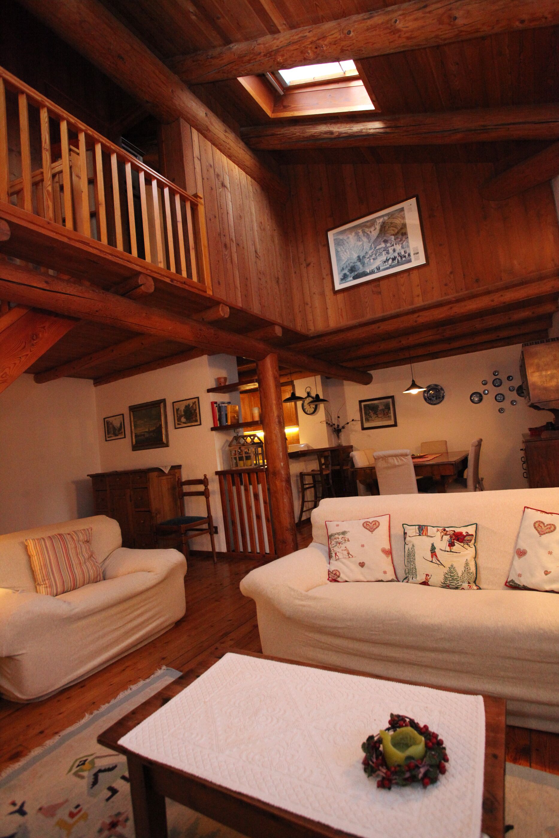 A cozy wooden interior with a high ceiling, a dining area, and a staircase.