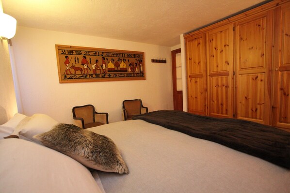 A bedroom with a large wooden wardrobe, a bed with a fur throw, and a wall painting. - Apartment Pré Saint Didier for rent / 6 - 8 people (PRE' SAINT DIDIER)