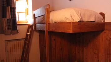 Un lit superposé en bois avec une échelle, une fenêtre avec des rideaux et un tableau accroché au mur.