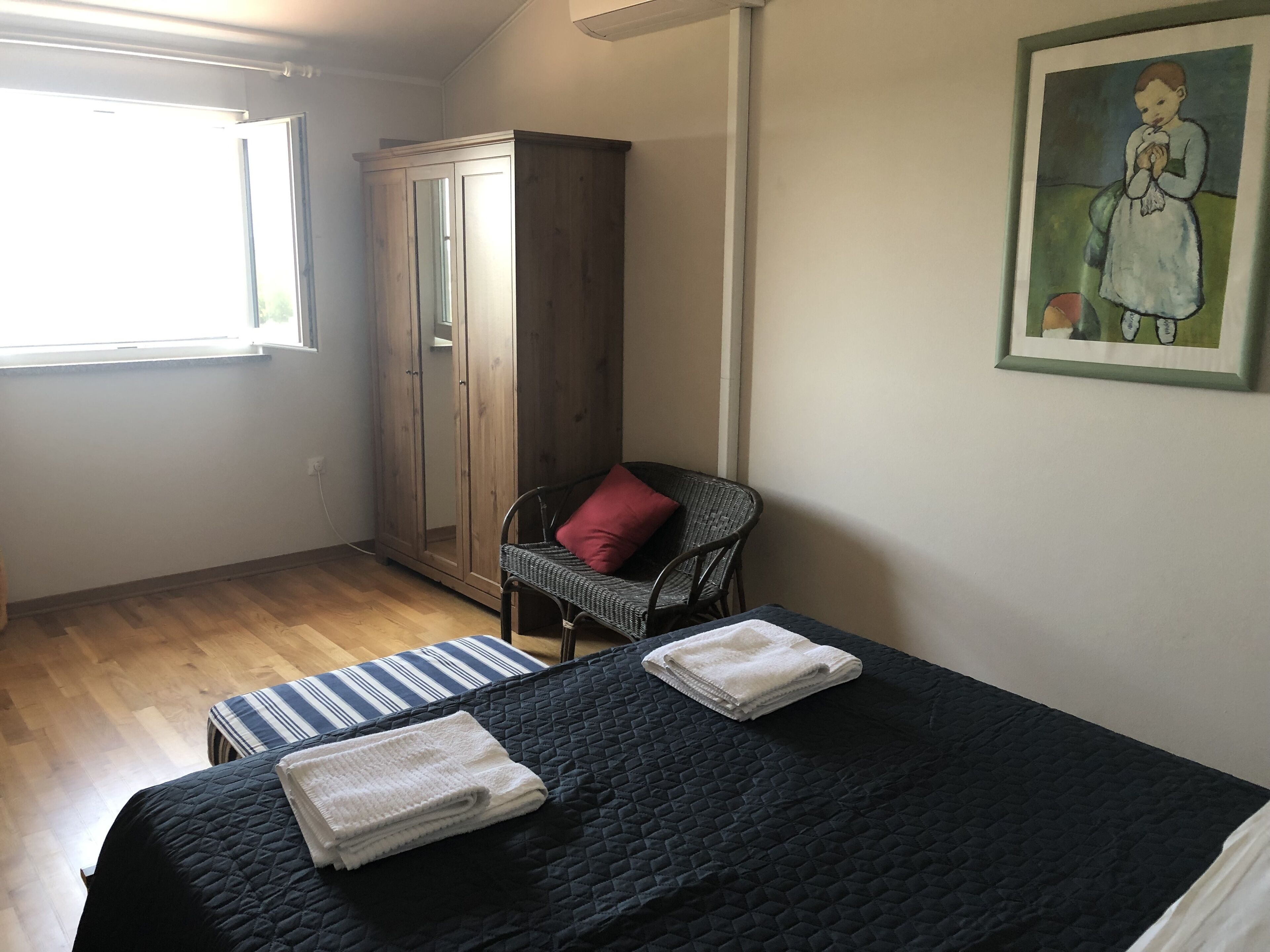 Ein Schlafzimmer mit Bett, Stuhl, Kleiderschrank und einem Bild an der Wand.