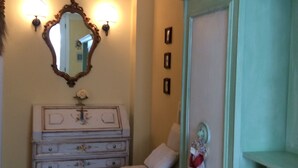 Une pièce comprenant une commode ancienne, un miroir et un meuble vert avec des étagères.