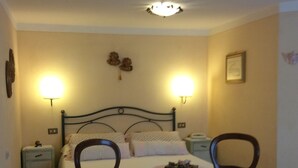 Une chambre à coucher avec un lit, deux chaises, une petite table et des lampes de chevet.