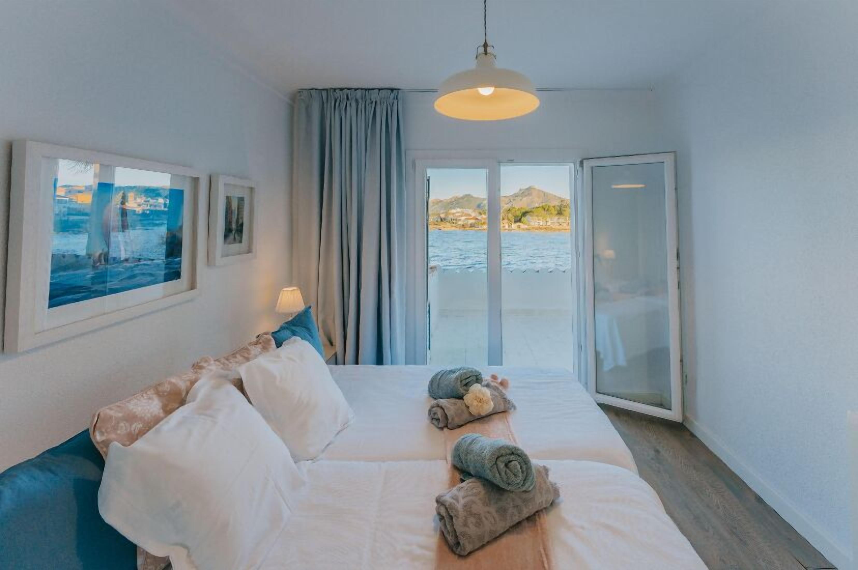 Une chambre d’hôtel avec un lit, une vue sur la mer, une fenêtre avec des rideaux et une porte.