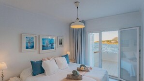 A hotel room with a bed, a nightstand, a lamp, and a view of the sea through large windows. - TRANQUILITY, REST AND RELAXATION BY THE SEA.  IN WINTER CENTRAL HEATING  (Alcudia)