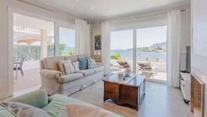 A spacious living room with a sofa, coffee table, and a view of the sea. - TRANQUILITY, REST AND RELAXATION BY THE SEA.  IN WINTER CENTRAL HEATING  (Alcudia)
