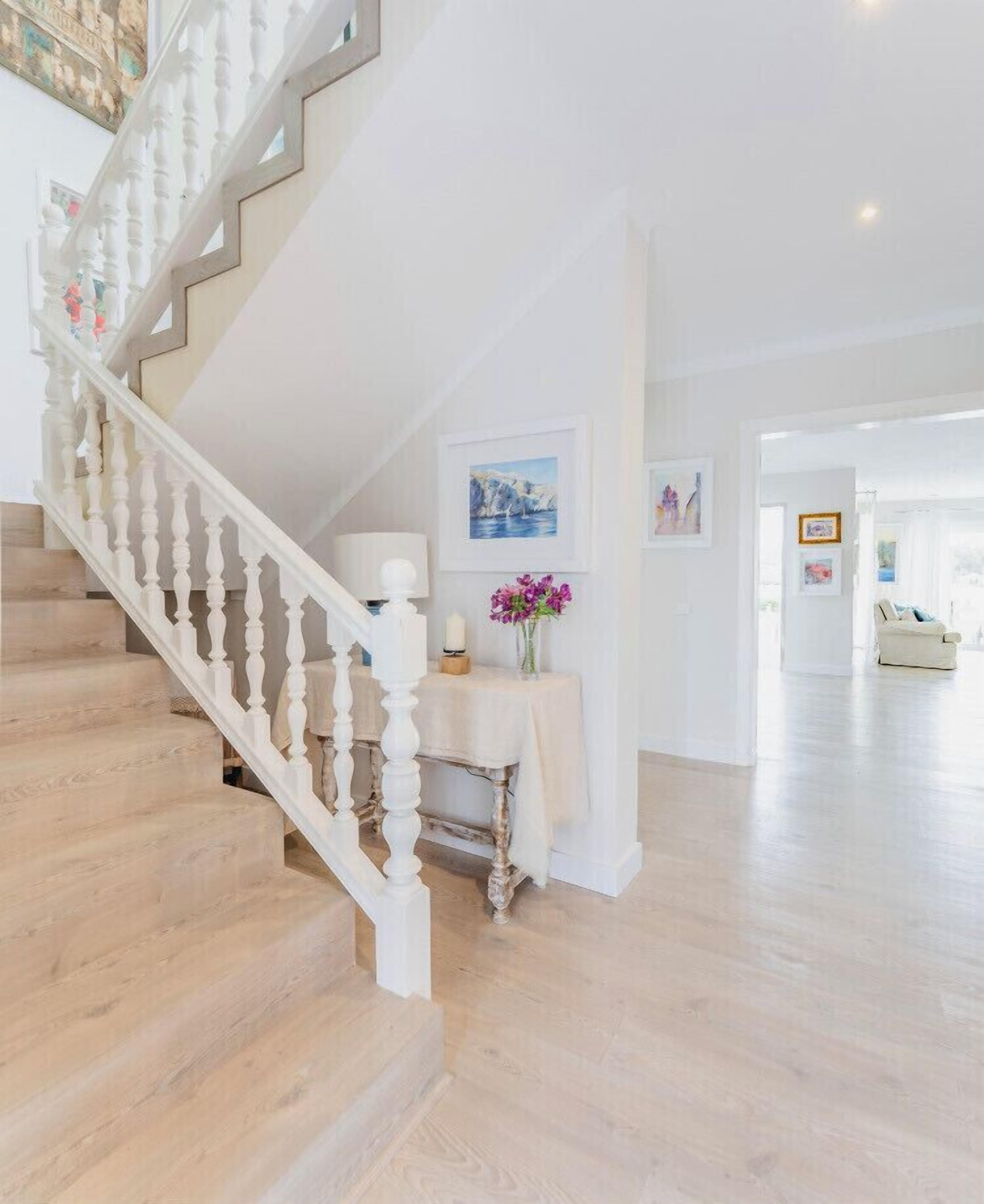 A staircase with white balusters leading to a landing with a table and a vase of flowers.