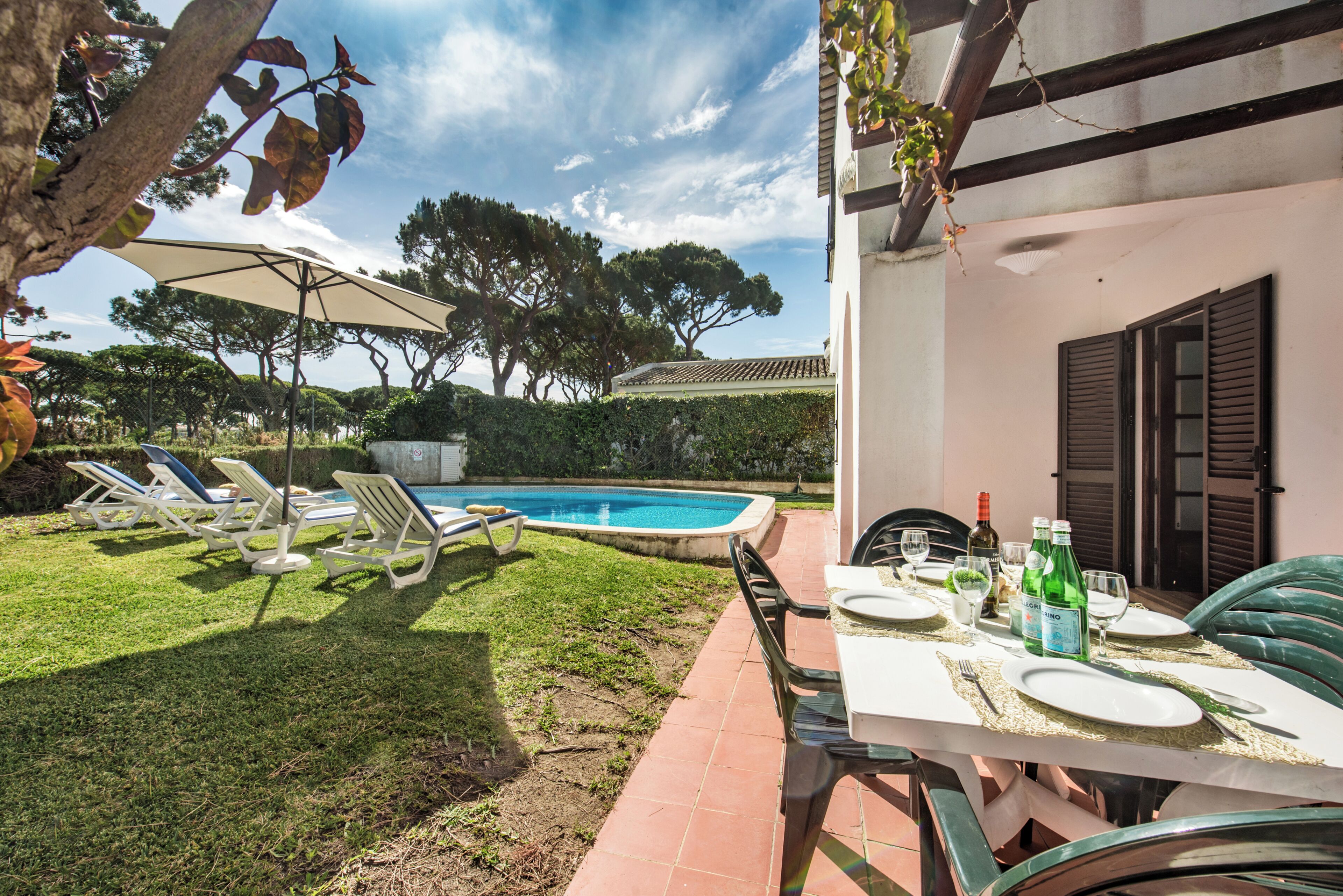 Un área junto a la piscina con sillones de descanso, una mesa de comedor para dos personas y vistas a la piscina.