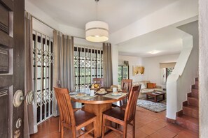 A dining area with a round wooden table, chairs, and a hanging light fixture.