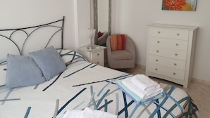 Une chambre à coucher comprenant un lit, une table de chevet, une commode, une chaise, un miroir et un tableau.