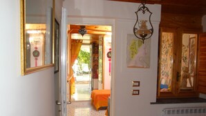 A hallway with a patterned floor, a bed with an orange bedspread, a radiator, and a mirror with a gold frame. - Cleopatra: holiday home with terrace, Sorrento and Amalfi coast (Massa Lubrense)