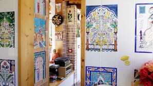 A room with a wooden ceiling, tiled walls with various patterns, a shelf with CDs, and a small statue. - Cleopatra: holiday home with terrace, Sorrento and Amalfi coast (Massa Lubrense)